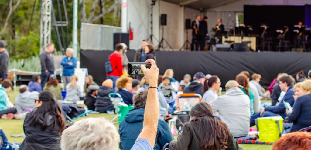 An elderly person recording a concert live on her cellphone